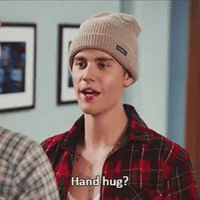 A Man Wearing A Plaid Shirt And A Beanie Is Asking For A Hand Hug GIF