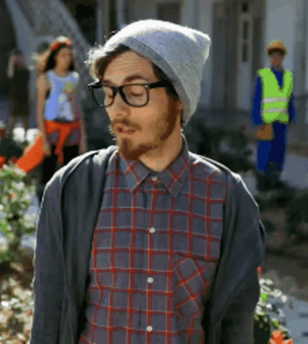 A Man Wearing A Plaid Shirt And A Beanie Looks Down GIF