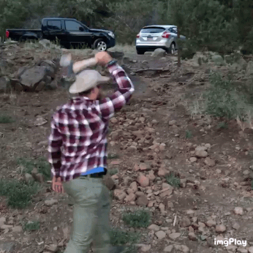 A Man Wearing A Plaid Shirt And A Cowboy Hat Throws A Rock At A Truck GIF