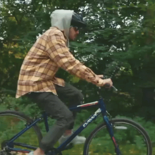 A Man Wearing A Plaid Shirt And A Helmet Is Riding A Dawes Bike GIF