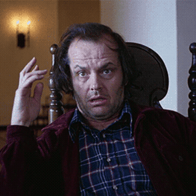 A Man Wearing A Plaid Shirt And A Red Jacket Is Sitting In A Chair GIF