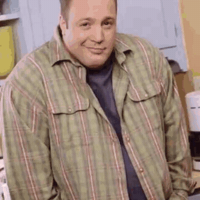 A Man Wearing A Plaid Shirt Is Standing In A Kitchen . GIF