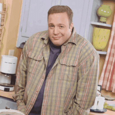 A Man Wearing A Plaid Shirt Is Standing In A Kitchen With His Hands In His Pockets GIF