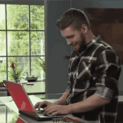 A Man Wearing A Plaid Shirt Is Typing On A Laptop GIF