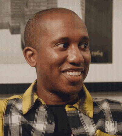 A Man Wearing A Plaid Shirt With The Letters Snl On The Bottom GIF
