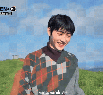 A Man Wearing A Plaid Sweater Is Smiling In A Field With The Words Sunsunarchives Written Below Him GIF