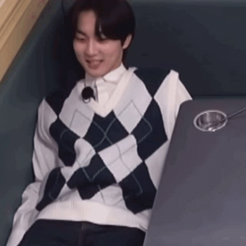 A Man Wearing A Plaid Vest Is Sitting At A Table With A Spoon In It . GIF