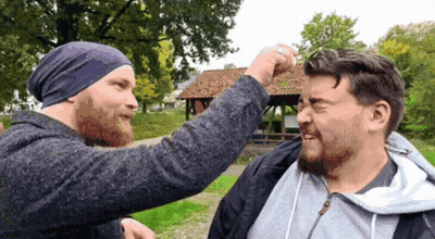A Man Wearing A Purple Beanie Is Punching Another Man 'S Head GIF