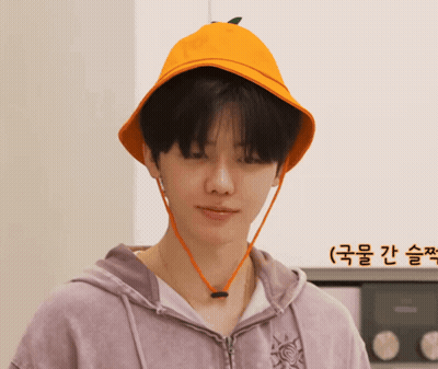 A Man Wearing A Purple Hoodie And An Orange Hat With A Green Leaf On It GIF