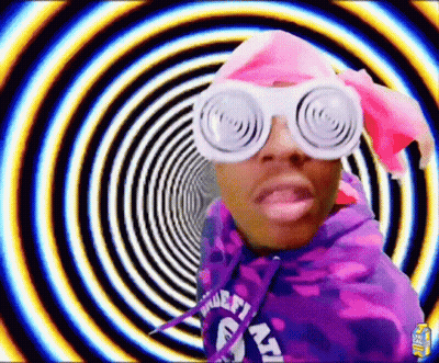 a man wearing a purple hoodie and white glasses is standing in front of a spiral .