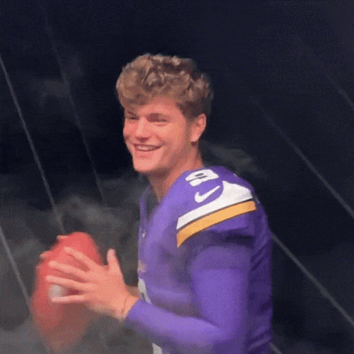 A Man Wearing A Purple Jersey With The Number 10 On It Holds A Football GIF