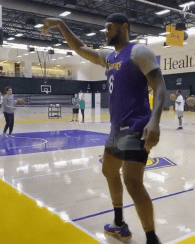 A Man Wearing A Purple Lakers Jersey Is Dancing On A Basketball Court GIF