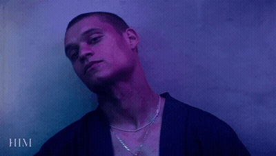 A Man Wearing A Purple Shirt And A Necklace With The Word Him Below Him GIF