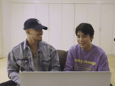 A Man Wearing A Purple Shirt That Says Unity Change Sits Next To Another Man GIF