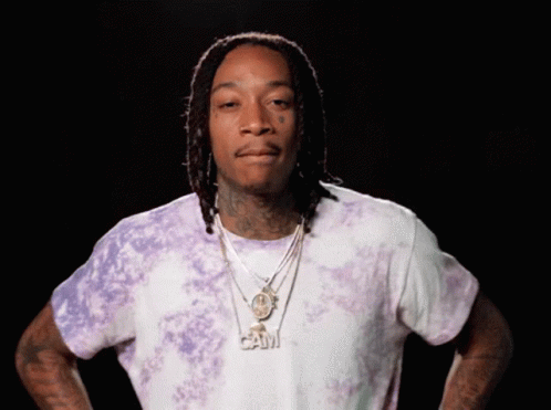 A Man Wearing A Purple Tie Dye Shirt Has A Necklace With The Word Cam On It GIF