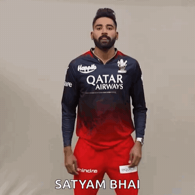 A Man Wearing A Qatar Airways Shirt And Red Pants Is Standing In Front Of A Wall . GIF