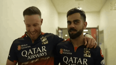 A Man Wearing A Qatar Airways Shirt Stands Next To Another Man GIF