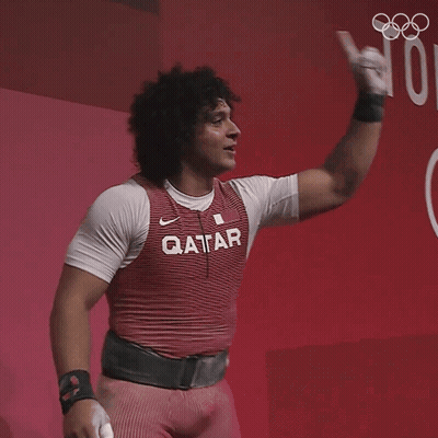 A Man Wearing A Qatar Shirt Holds His Fist Up GIF
