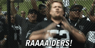 A Man Wearing A Raiders Jersey Stands In Front Of A Crowd GIF