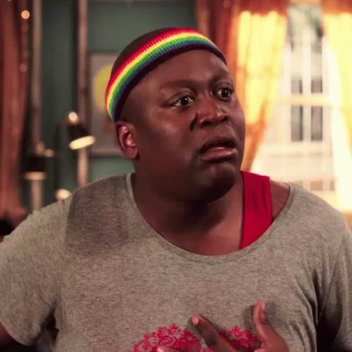 A Man Wearing A Rainbow Headband And A Gray Shirt Is Making A Funny Face GIF