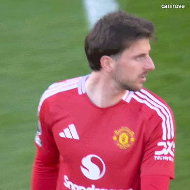 A Man Wearing A Red Adidas Shirt Is Standing On A Green Field . GIF