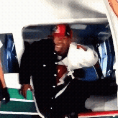 A Man Wearing A Red And Black Hat Is Getting Out Of A Helicopter GIF
