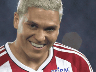 A Man Wearing A Red And White Jersey That Says Gripac Smiles GIF