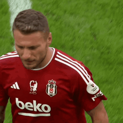 A Man Wearing A Red Beko Shirt Stands On A Field GIF