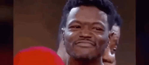 A Man Wearing A Red Boxing Glove Is Smiling . GIF