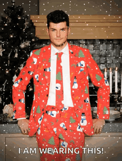 A Man Wearing A Red Christmas Suit With Snowmen And Trees On It GIF