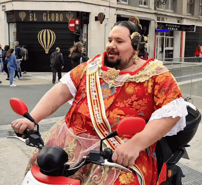 A Man Wearing A Red Dress Is Riding A Motorcycle In Front Of A Store Called El Globo GIF