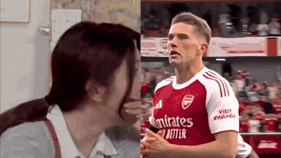A Man Wearing A Red Emirates Shirt Is Being Kissed By A Woman GIF