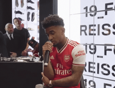 A Man Wearing A Red Fly Emirates Jersey Holds A Microphone GIF