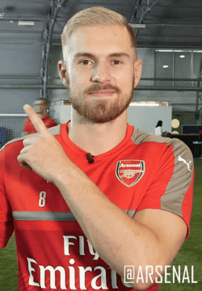 A Man Wearing A Red Fly Emirates Soccer Jersey Is Pointing Up GIF