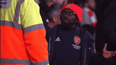 A Man Wearing A Red Hat And A Black Jacket With Emirates Fly Better Written On It GIF