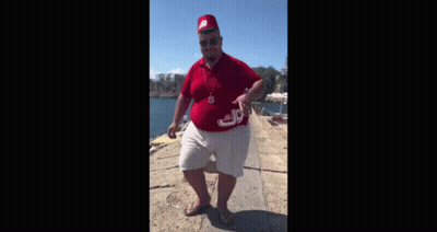A Man Wearing A Red Hat And A Red Shirt Is Standing On A Pier . GIF
