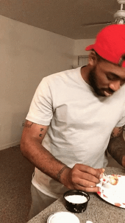 A Man Wearing A Red Hat And A White Shirt Has A Tattoo On His Arm That Says ' T.e. ' GIF