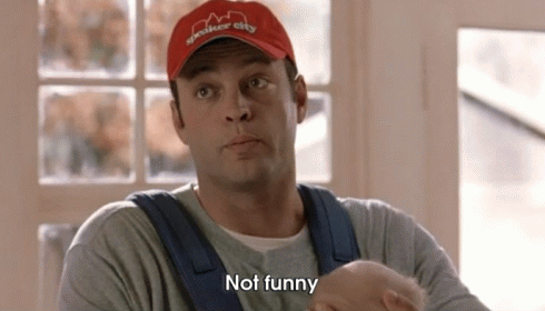 A Man Wearing A Red Hat And Overalls Is Holding A Baby And Saying `` Not Funny '' . GIF