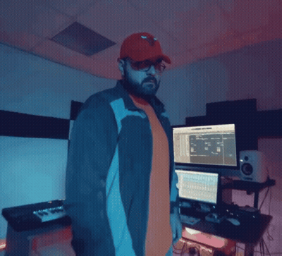 A Man Wearing A Red Hat And Sunglasses Is Standing In Front Of A Computer Monitor GIF
