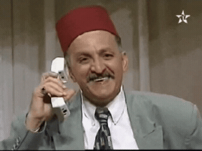 A Man Wearing A Red Hat And Tie Is Talking On A Cell Phone . GIF