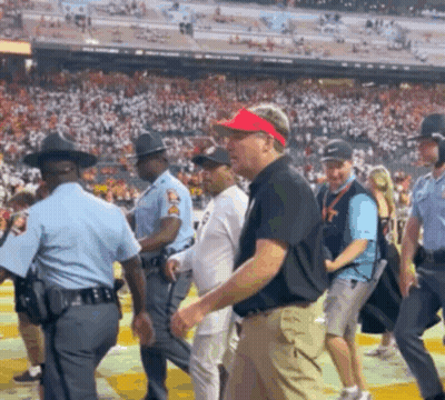 A Man Wearing A Red Hat And Visor Is Walking In A Crowd GIF