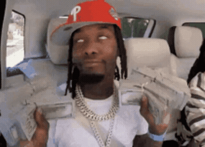 A Man Wearing A Red Hat Is Holding A Bunch Of Money In His Hands . GIF
