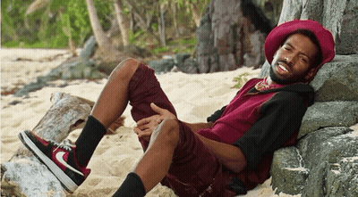A Man Wearing A Red Hat Is Laying On A Rock GIF