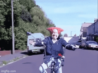 A Man Wearing A Red Hat Is Riding A Bike On A Street GIF