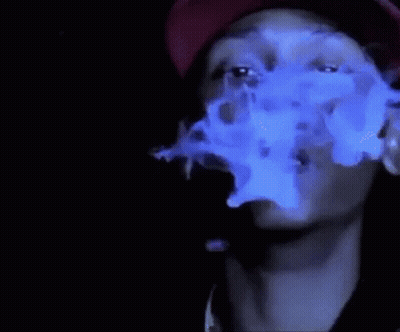 A Man Wearing A Red Hat Is Smoking A Cigarette With Blue Smoke Coming Out Of His Mouth . GIF