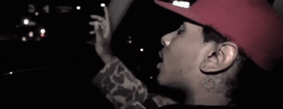 A Man Wearing A Red Hat Is Sticking Out His Tongue . GIF