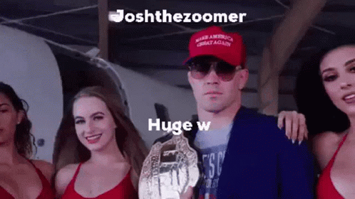 A Man Wearing A Red Hat That Says Make America Great Again Is Holding A Championship Trophy Surrounded By Three Women . GIF