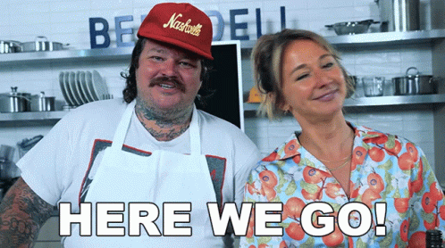 A Man Wearing A Red Hat That Says Nashville Stands Next To A Woman In A Blue Shirt That Says Here We Go GIF