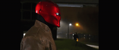 A Man Wearing A Red Helmet And A Leather Jacket Is Standing In The Dark . GIF