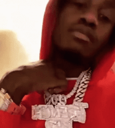 A Man Wearing A Red Hoodie And A Necklace With A Cross On It GIF